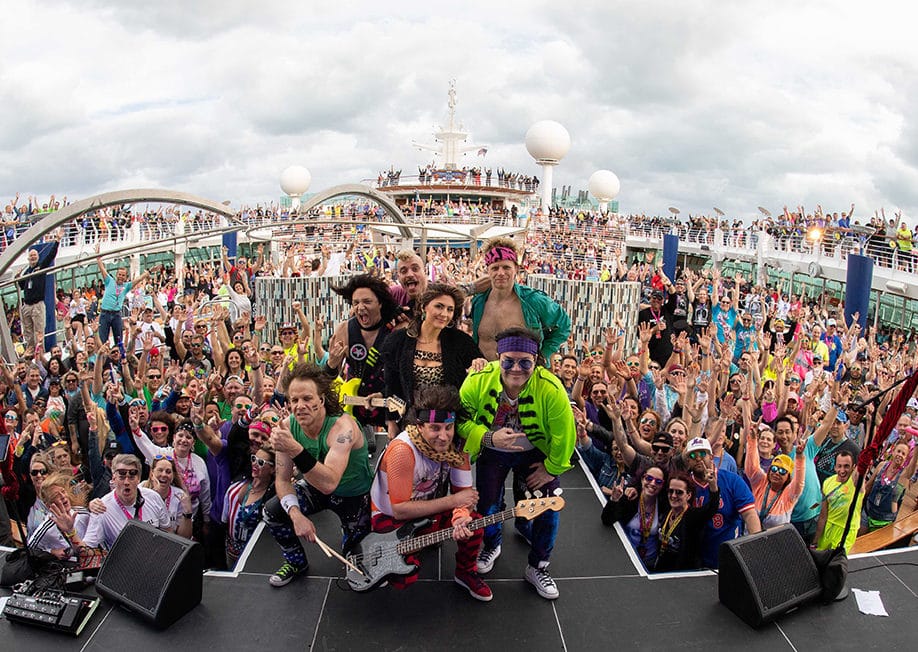 A photo of an 80s tribute bands in front of a crowd on a cruise ship, booked as cruise ship entertainment for an 80s themed event.