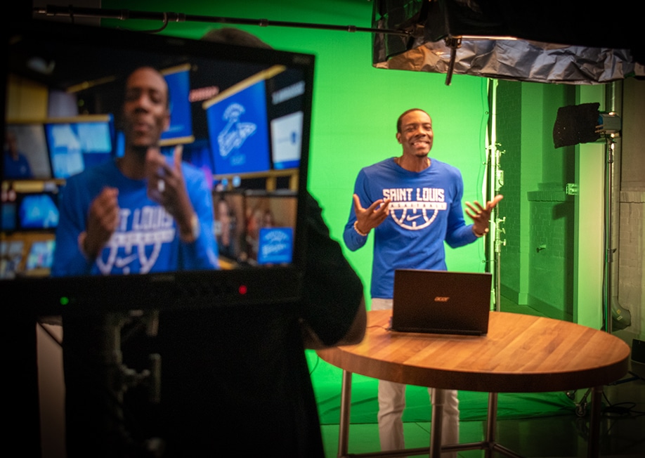 A man records in front of a green screen for virtual meetings being produced