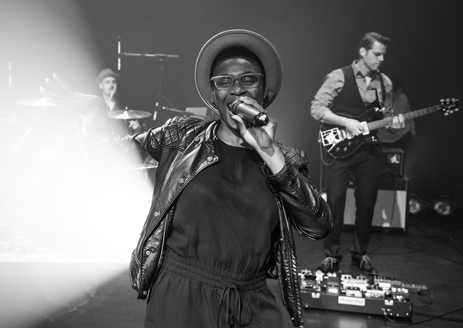 A black and white image of a lead singer performing with a band behind them for wedding entertainment.