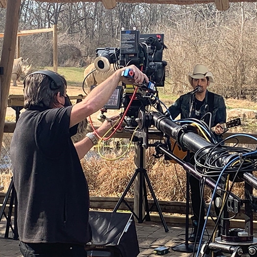 A man uses a camera set-up to record a musician for virtual event production